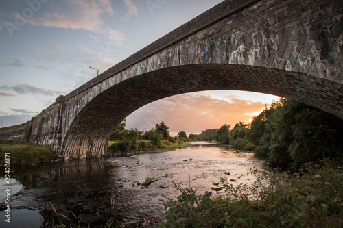 Llandeilo single arch bridge with the river Tywi at sunset. pink and orange glow reflecting on the river. photo