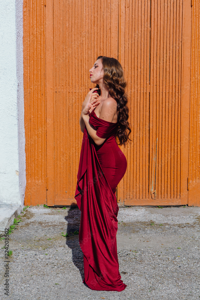 Beautiful young woman in a long red evening gown with a train