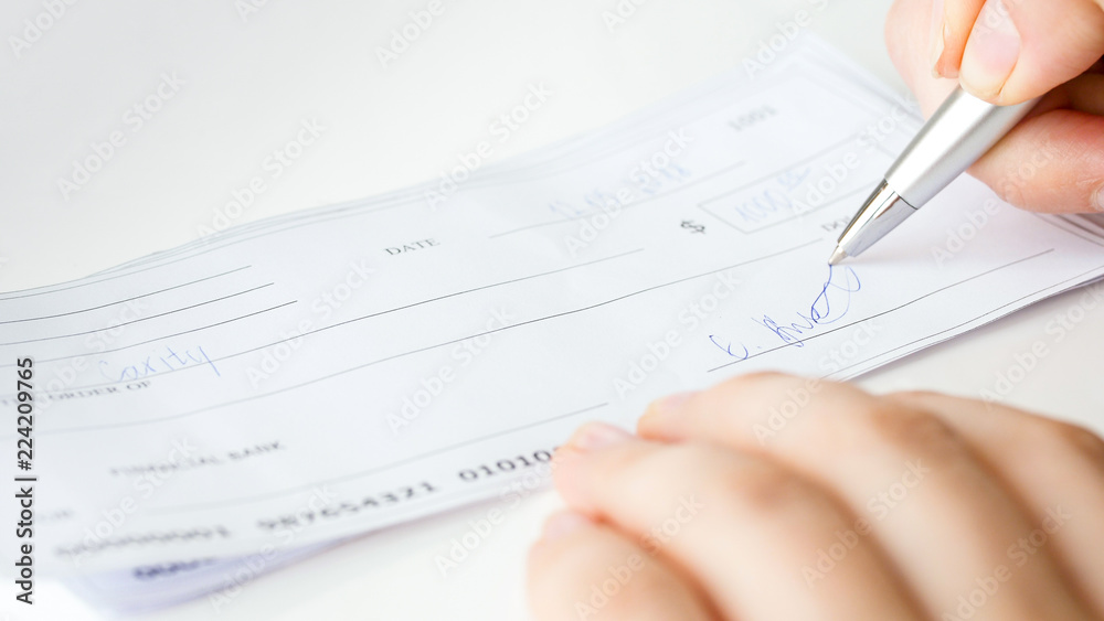 Closeup image of businesswoman signing personal bank cheque Closeup image of businesswoman signing personal bank cheque