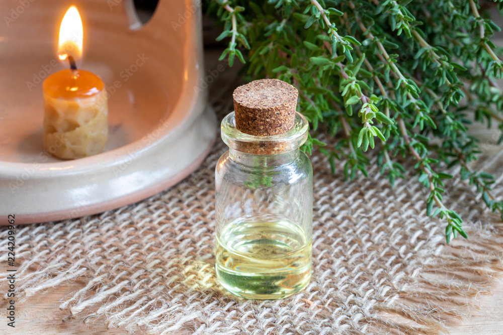 A bottle of thyme essential oil with fresh thyme twigs A bottle of thyme essential oil with fresh thyme twigs