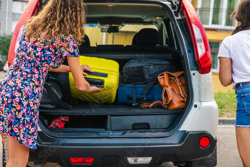 two woman packing luggage in car trunk photo