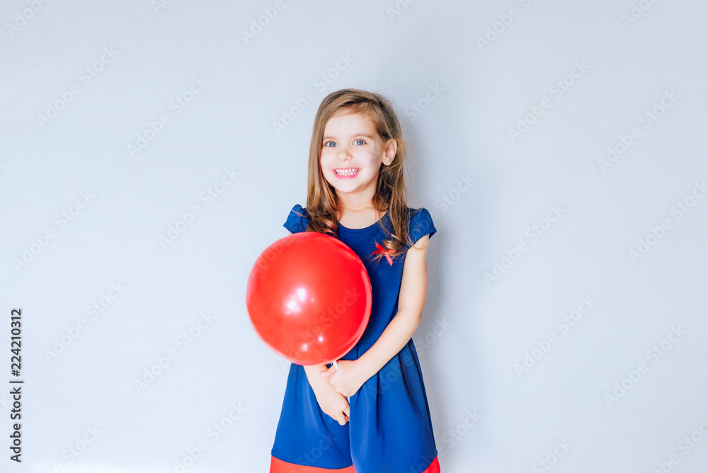 Funny beautiful little girl with a red balloon stands on a gray background. black Friday. Funny beautiful little girl with a red balloon stands on a gray background. black Friday.
