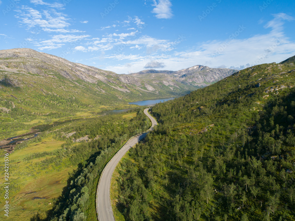 Aerial view of a road leading behind mountains at summer