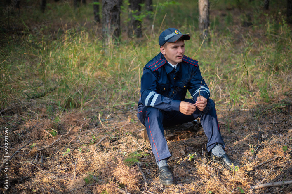 Policeman sits on the grass in the forest and thinks Policeman sits on the grass in the forest and thinks