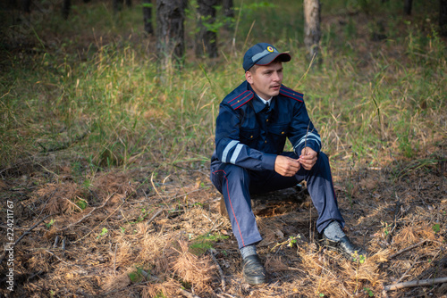Policeman sits on the grass in the forest and thinks