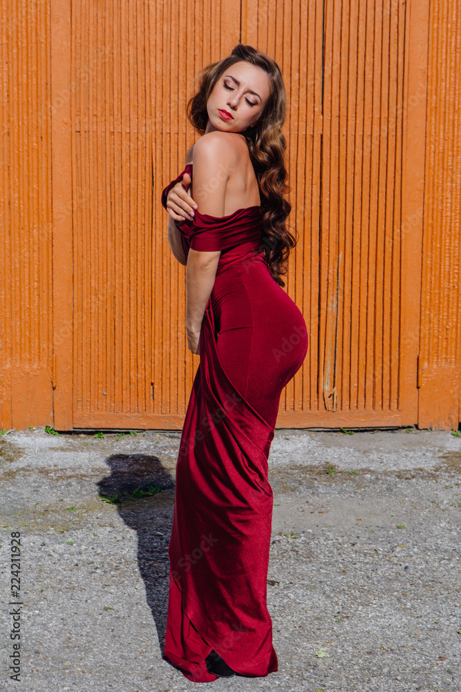 Beautiful young woman in a long red evening gown with a train Beautiful young woman in a long red evening gown with a train
