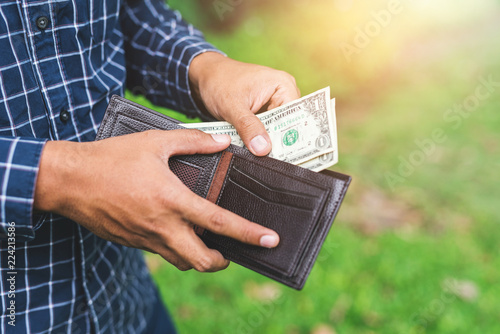 Hand man putting money in wallet.