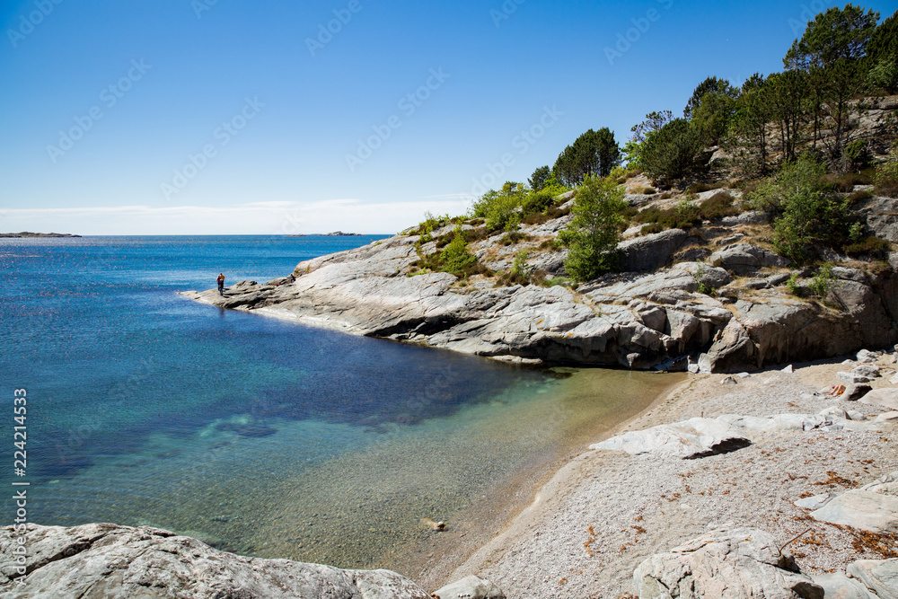 Serene scandinavian summer landscape on south coast of Norway. Sunny rocky beach with turquoise quiet water.