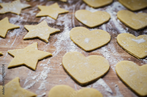 Christmas baking. Making gingerbread biscuits. Cookie dough in heart and star shape on kitchen counter.