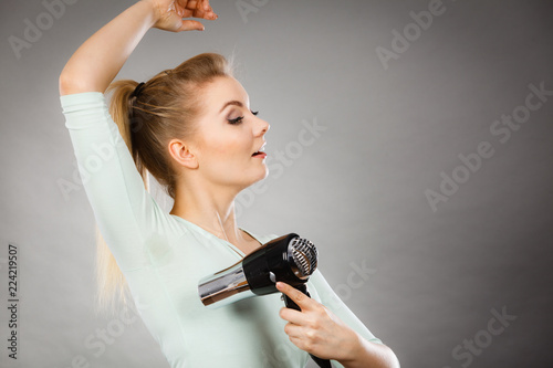 Woman drying armpit with hair dryer