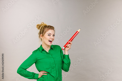 Happy woman holding big oversized pencil