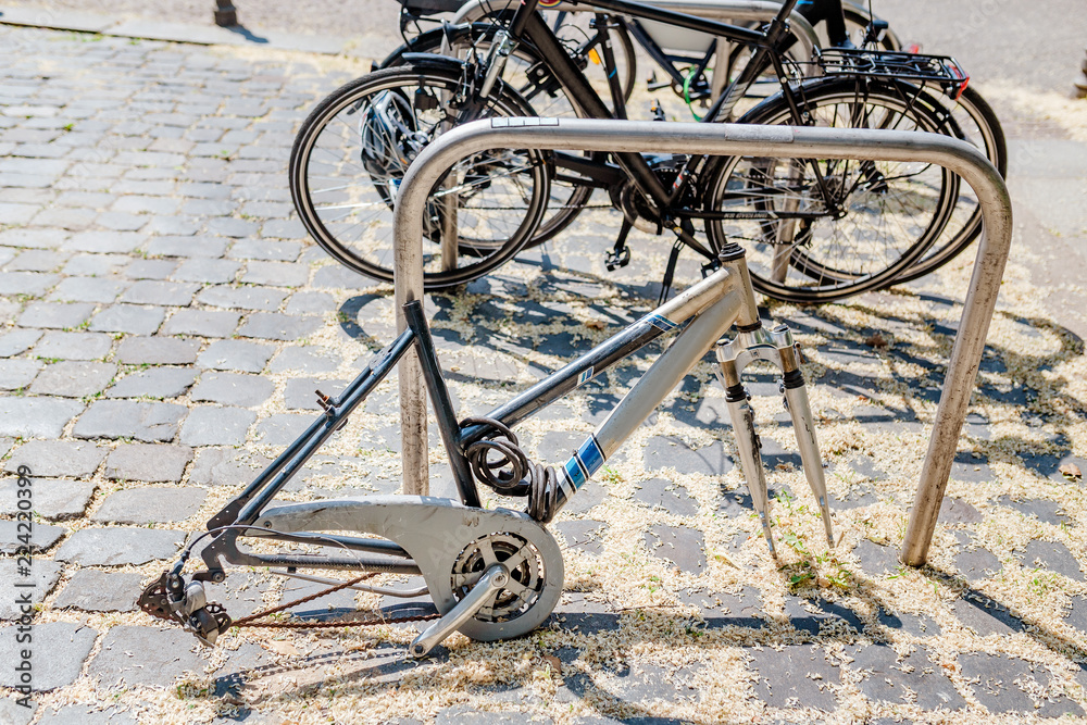 Obraz premium Bicycle frame without wheels, with locker lay on the street parking, stolen bicycle concept