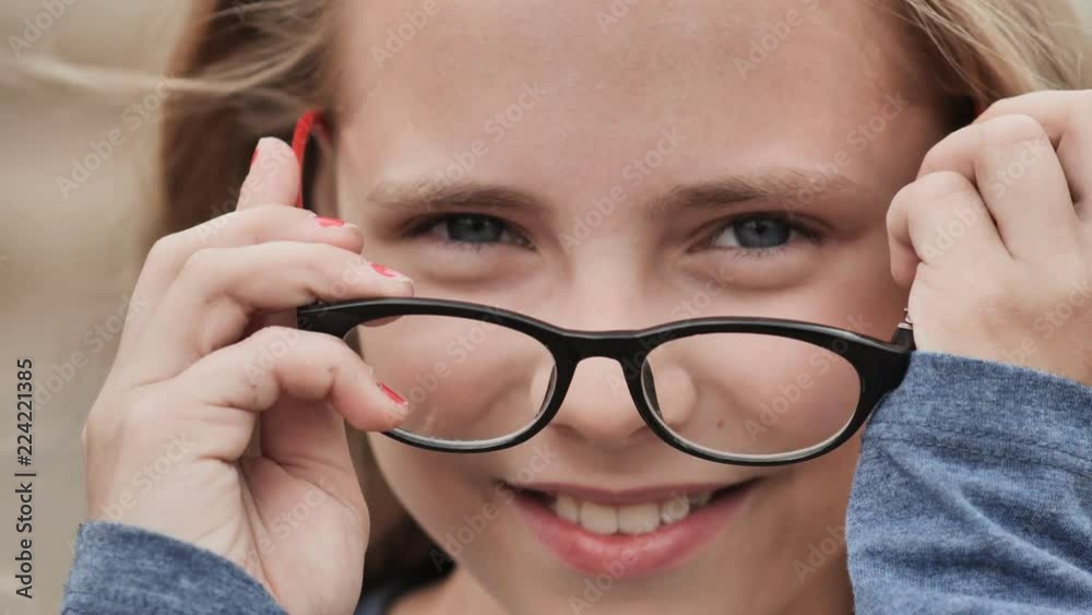 Smiling blonde 10 year old girl dresses glasses. Face close-up.