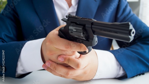 Closeup image of man in suit holding and aiming with gun