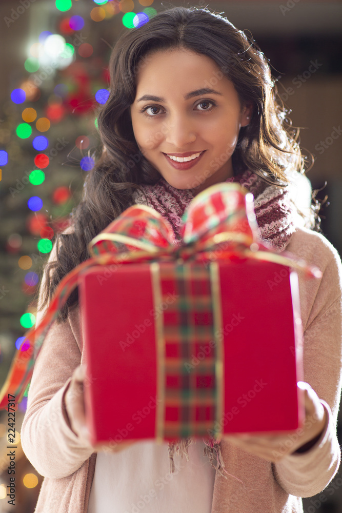 Woman with gift and christmas tree in the background Woman with gift and christmas tree in the background
