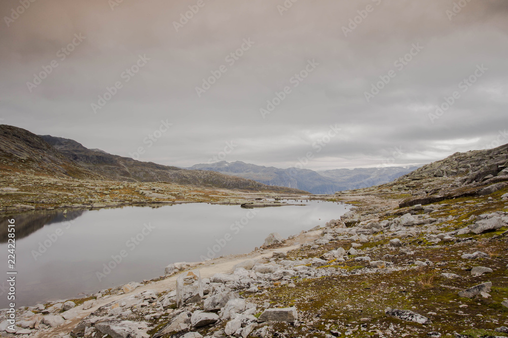 Fototapeta premium Rugged dramatic mountain landscape in norway cloudy dramatic day with calm lake