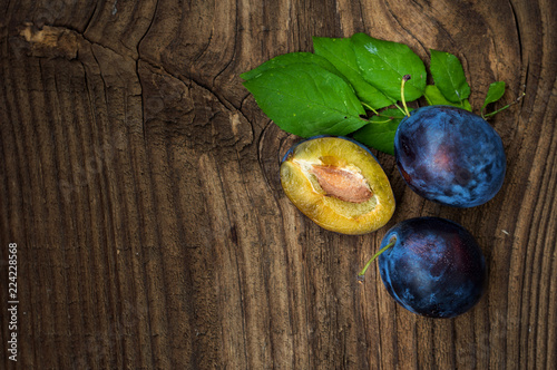 Fresh blue plums on wood table background. Sweet autumn fruit. Delicious and healthy raw food full of vitamins.