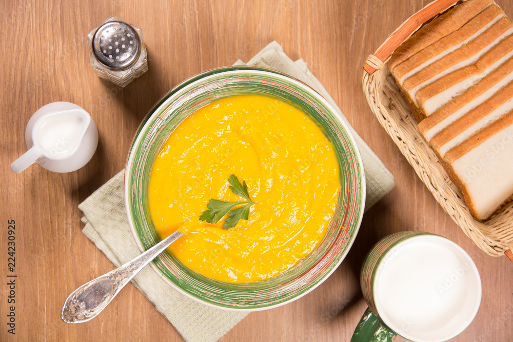Pumpkin cream soup in a green ceramic plate on the kitchen table Pumpkin cream soup in a green ceramic plate on the kitchen table