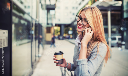 Fotografie Business woman drinking coffee and talking on a mobile phone outdoor
