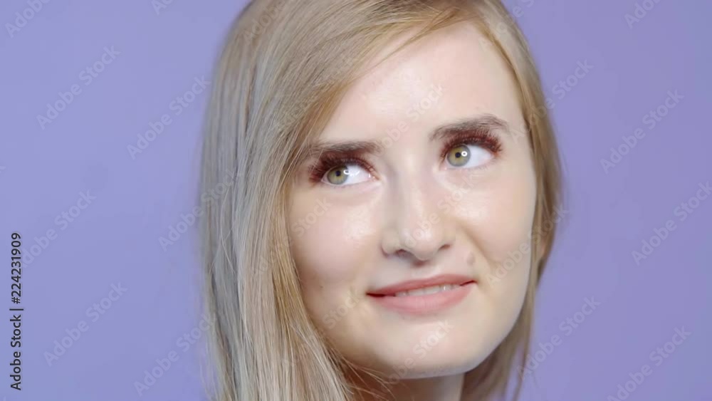 Cute young blonde model posing indoor, woman posing indoor isolated on purple background.