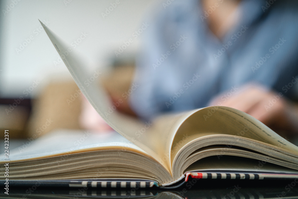Girl flips a page while reading a book, blurry background Girl flips a page while reading a book, blurry background