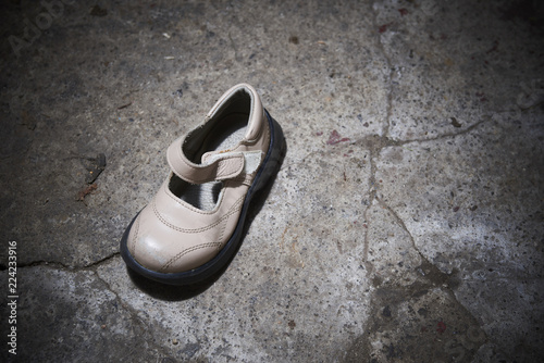 Abandoned baby shoe lying on old concrete floor. Lost children's shoes.