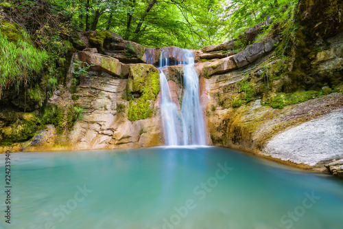 Beautiful waterfall in mountain of Caucasus. Summer landscape with waterfall and water stream in forest of Caucasus mountain.