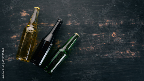 Three bottles of beer on a wooden background. Free space for text. Top view.