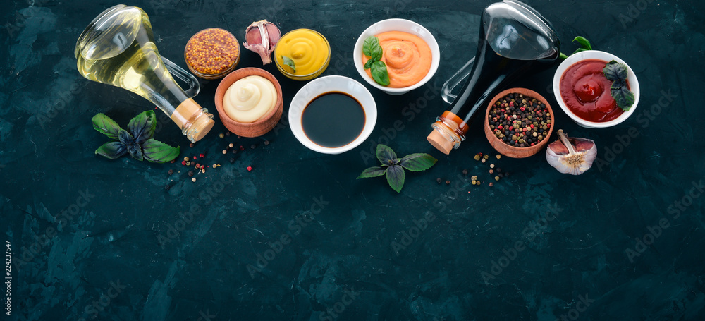 Set of sauces - Ketchup, mayonnaise, mustard, soy sauce, barbecue sauce, pepper and spices. On a black stone background. Top view. Free space for text. Set of sauces - Ketchup, mayonnaise, mustard, soy sauce, barbecue sauce, pepper and spices. On a black stone background. Top view. Free space for text.