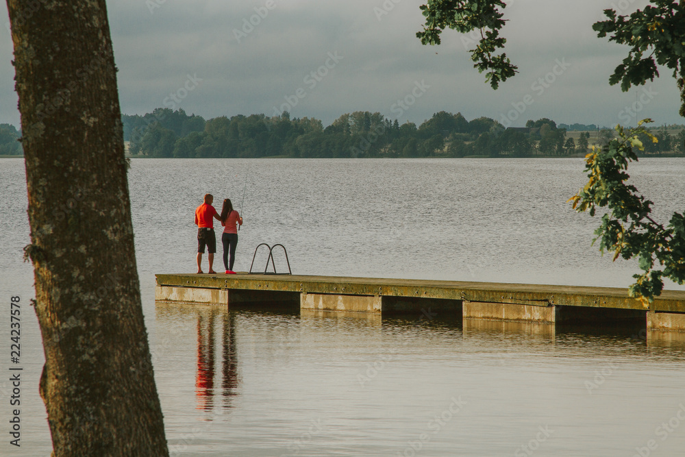 A boat pier on a still lake with couple fishing