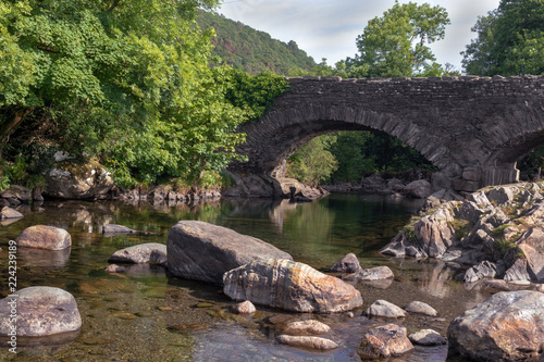 Old stone bridge over River Duddon in Ulpha in the Lake District National Park  UK. Scenic view of English countryside on a sunny day