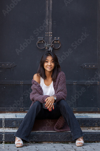 beautiful happy Asian girl sitting on the stairs near to house photo
