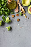 Variety of fresh green vegetables and nuts on grey concrete background for the healthy and vegetarian nutrition. Broccoli, avocado, parsley, walnuts and pine nuts. Fresh organic raw produce.