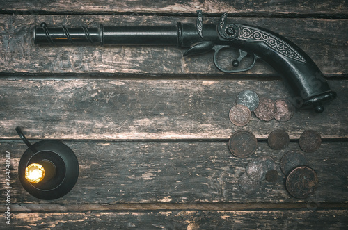 Musket gun, money and burning candle on wooden table background. Duel.