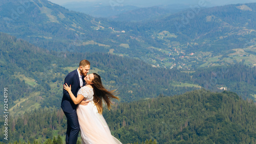 cute embrace of newlyweds on top of the mountain and the wind blowing the hair of the bride