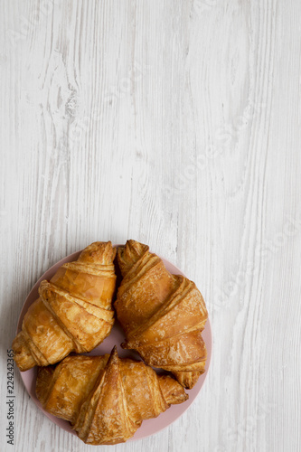 Fresh croissants on pink plate, top view. White wooden background. Overhead, from above, flat lay. Copy space.