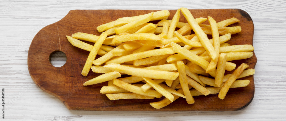French fries on rustic wooden board on a white wooden background, top view. From above, overhead. French fries on rustic wooden board on a white wooden background, top view. From above, overhead.