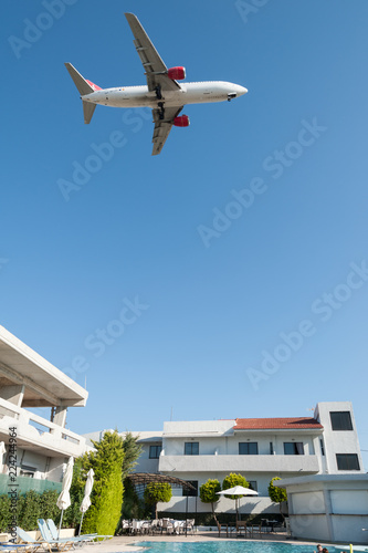 Airplane passing through above tourists while on holiday on Greek Island of Rhodes.