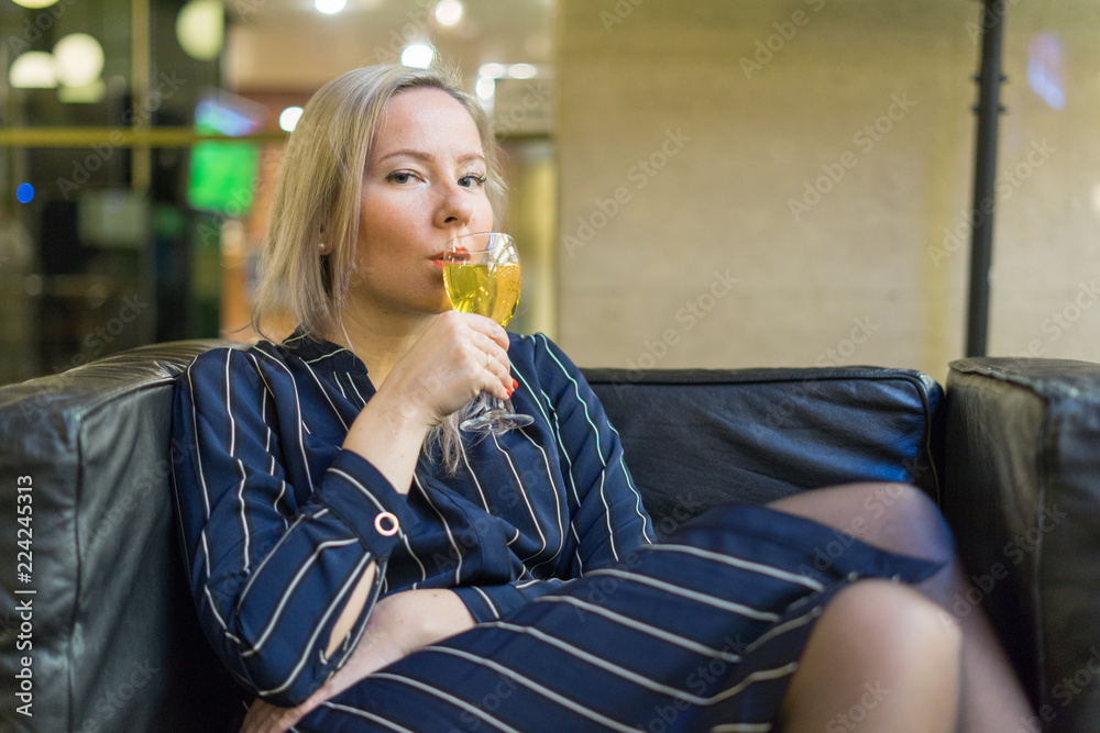 Young girl on a leather chair drinking white wine Young girl on a leather chair drinking white wine