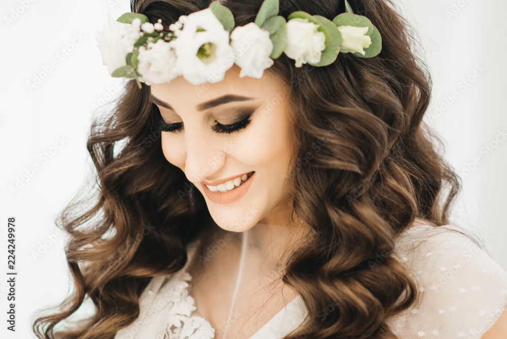 Gorgeous Beautiful Bride portrait with wedding makeup and long curly hair wears cristal wreath and bridal lace dress.
