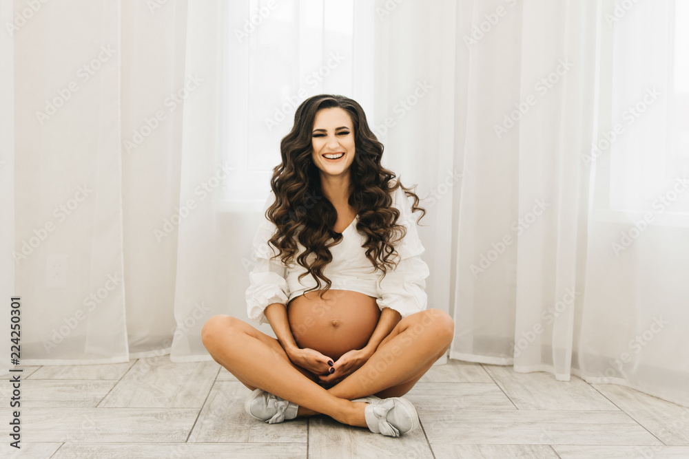 Stylish young pregnant girl in white clothes with curls and naked . Photo session waiting for the baby Stylish young pregnant girl in white clothes with curls and naked . Photo session waiting for the baby