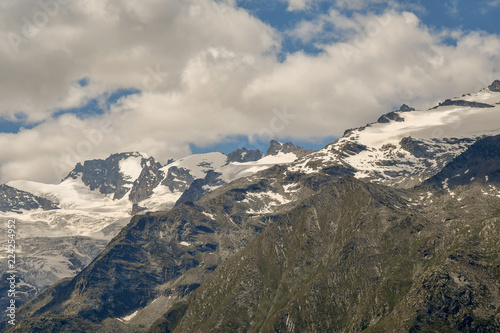 Cime di montagna con ghiacciai perenni e cielo azzurro con nubi in Valle d'Aosta, Alpi Italiane