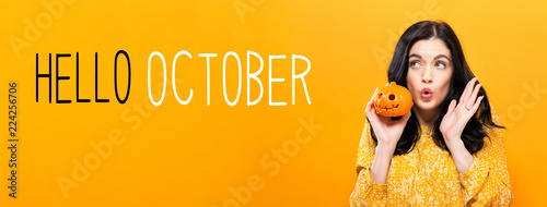 Hello October with young woman holding a pumpkin