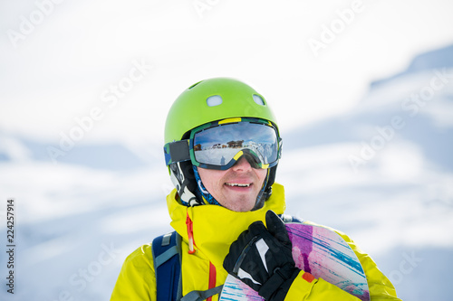 Photo of sportive man with snowboard against background of mountains