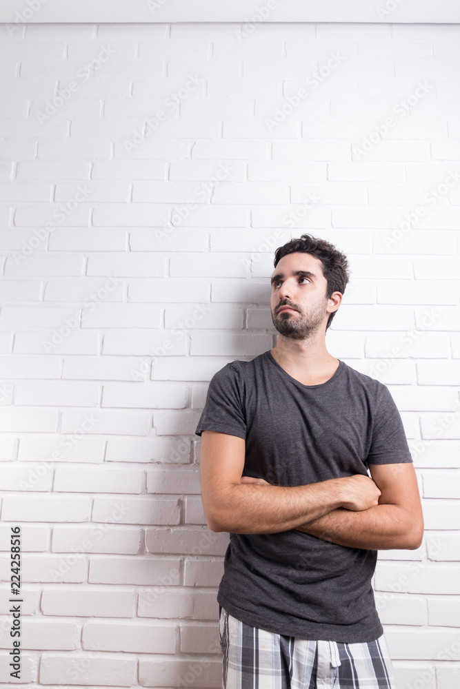 young white man wearing social outfit standing and posing in front of white brick wall young white man wearing social outfit standing and posing in front of white brick wall