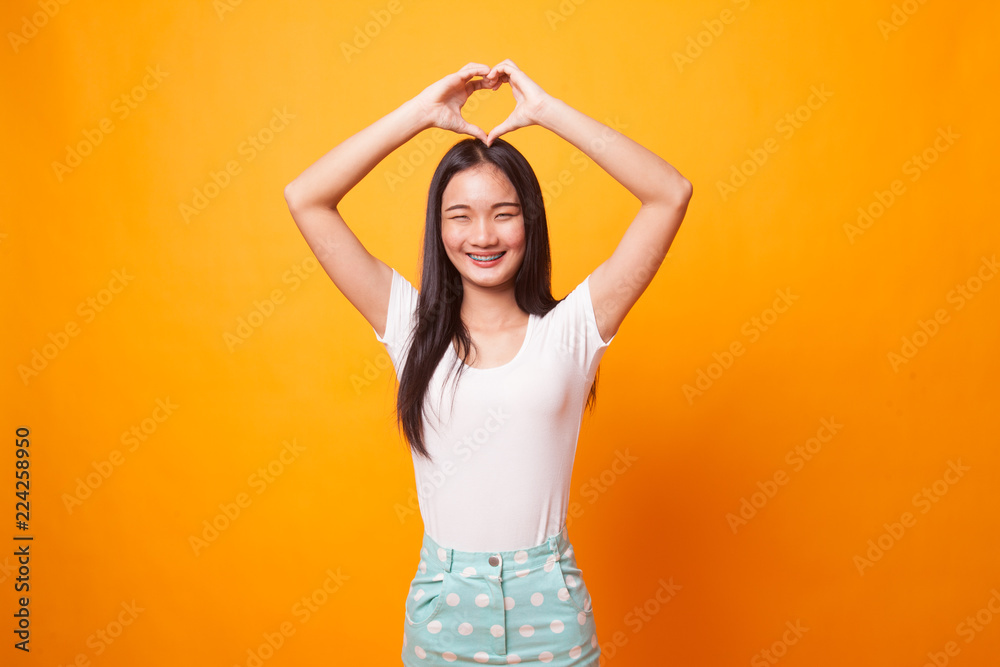 Young Asian woman gesturing heart hand sign. Young Asian woman gesturing heart hand sign.