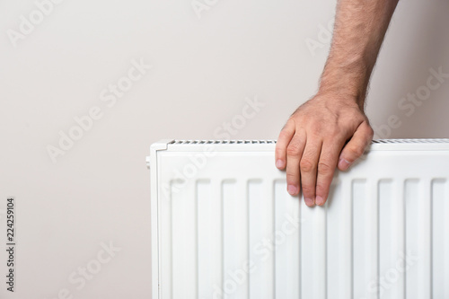 Wallpaper Mural Man warming hand on heating radiator against color background. Space for text Torontodigital.ca