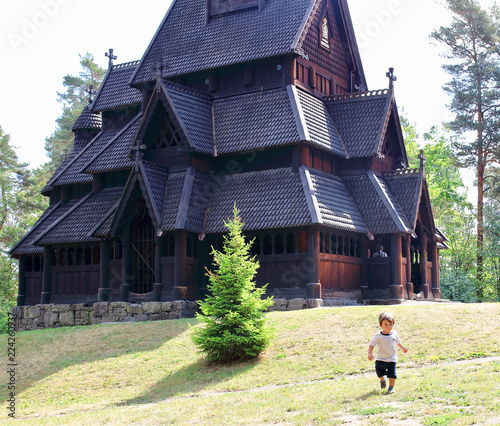 Little two years old boy running and playing in front of the Gol Church,  a stave church originally built in Gol city, but now located in the Norwegian Museum of Cultural History at Bygdy in Oslo. photo