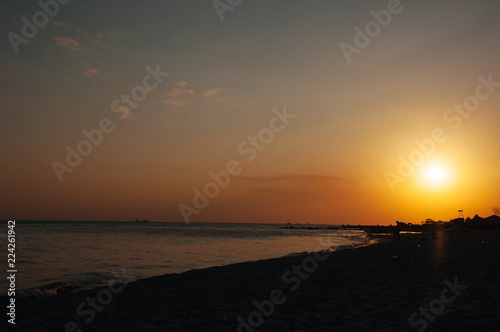 A warm orange sunset on the shore of the ocean, the sea, draws silhouettes in the sunset of a summer