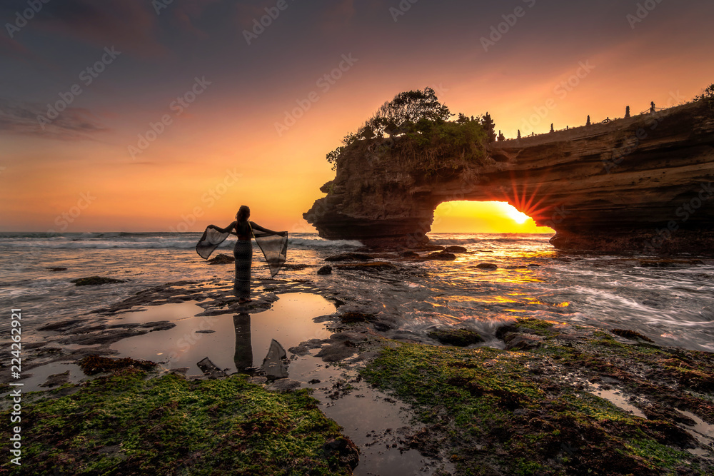 Silhouette woman standing at Pura Batu Bolong Temple in sunset background, Lombok, Indonesia
